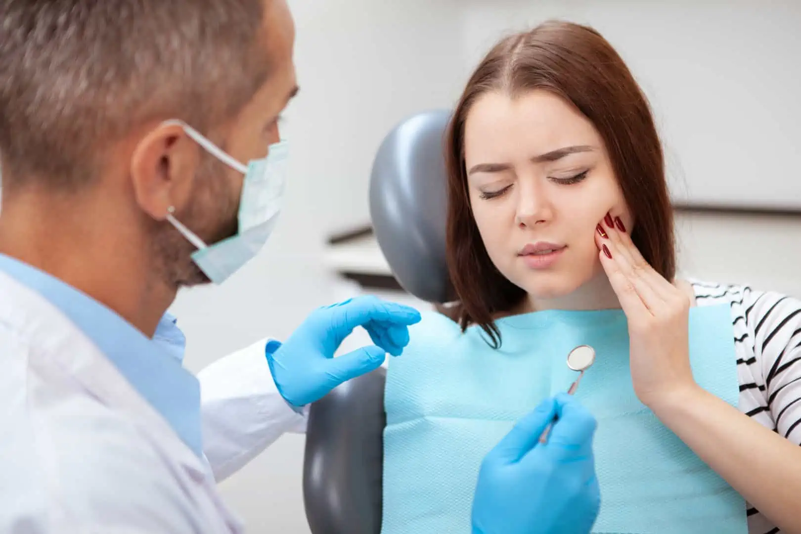 Man holding his jaw in discomfort from sudden tooth pain