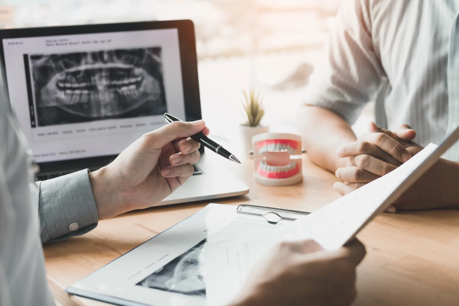 Dentist reviewing a panoramic X-ray and jaw model with a patient
